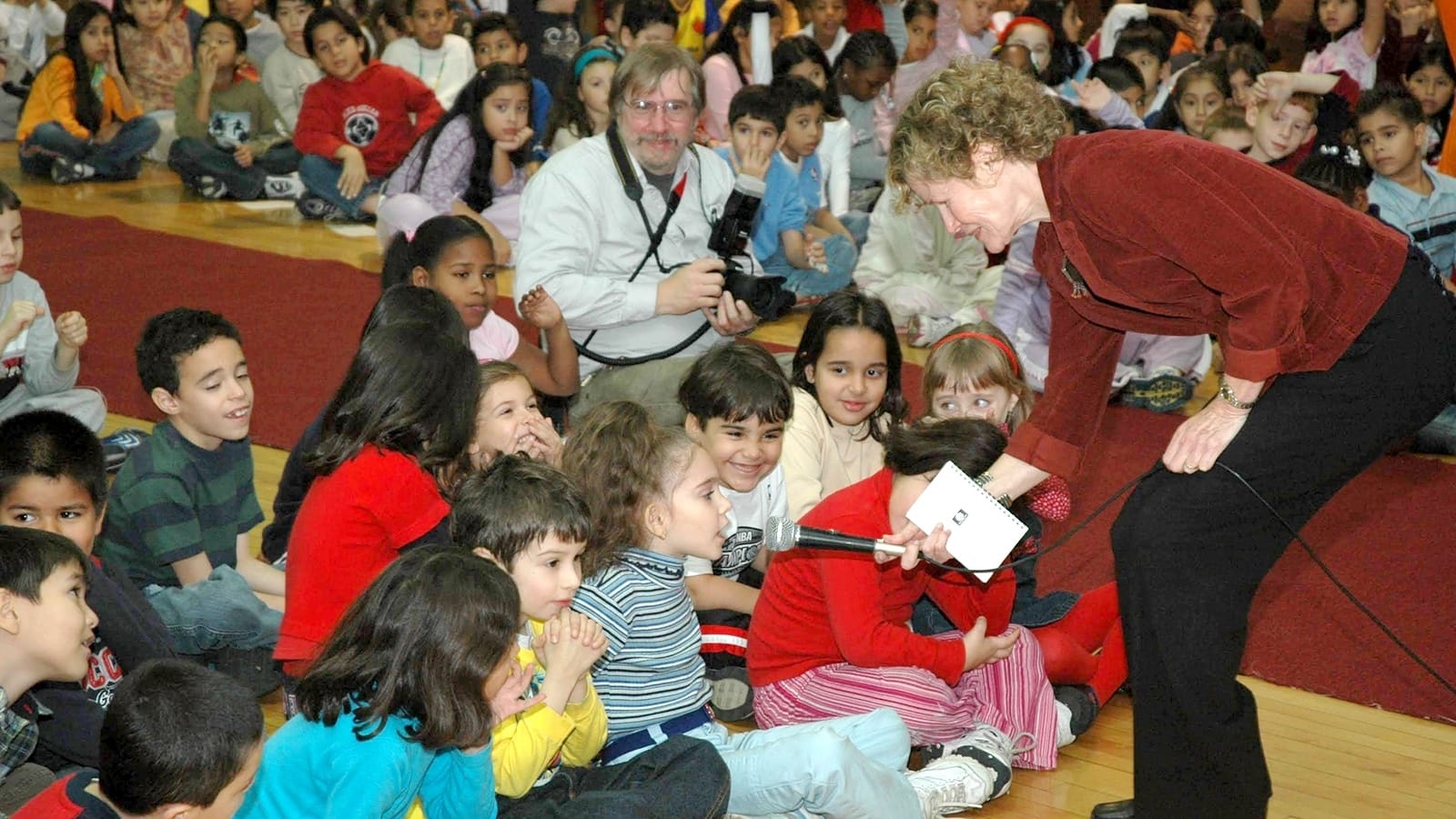 Judy Blume interacts with schoolchildren in an auditorium