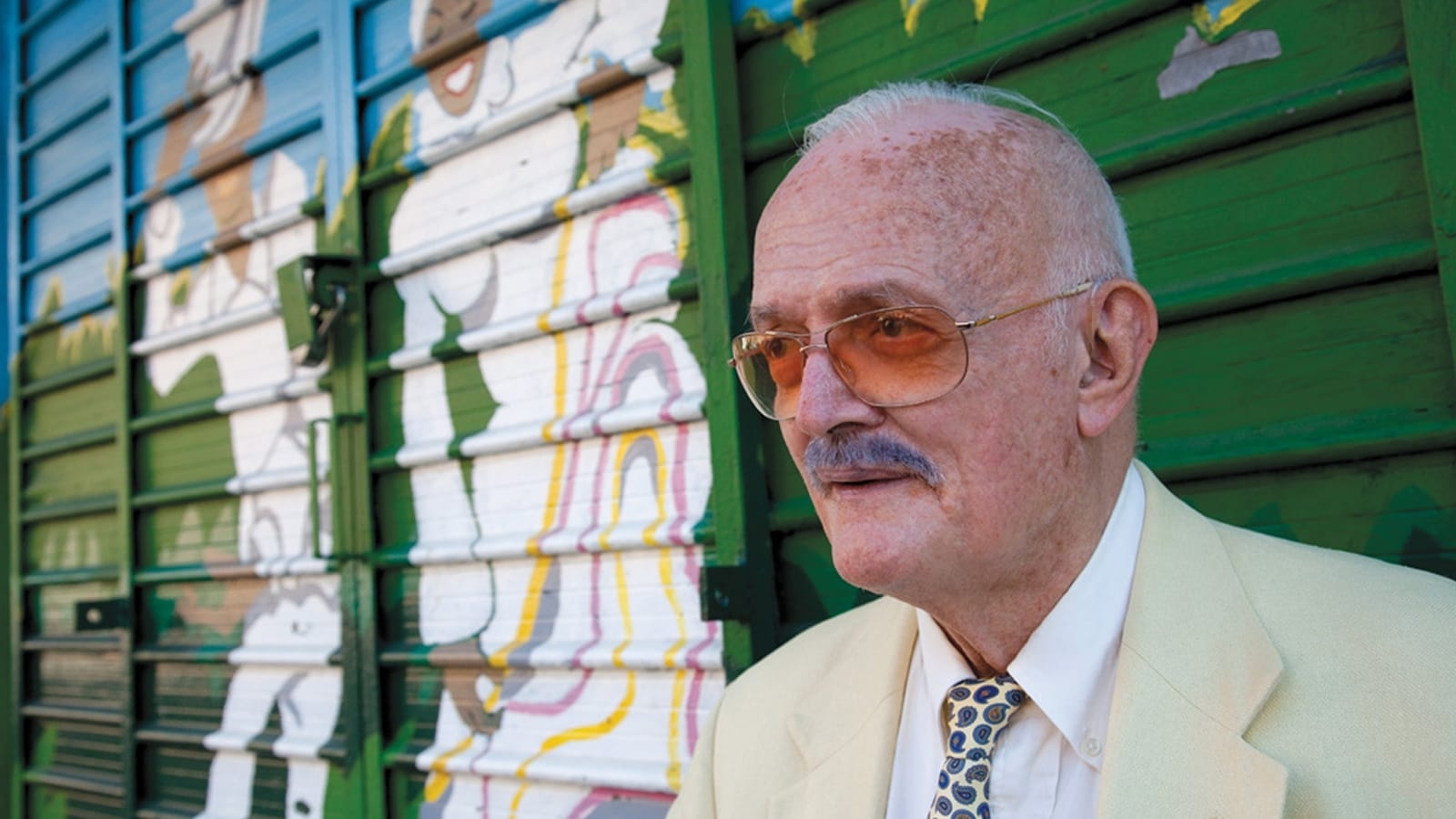 Robert Farris Thompson stands in front of a mural in Harlem